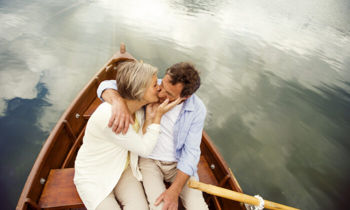 Senior couple kissing on boat on mountain tarn